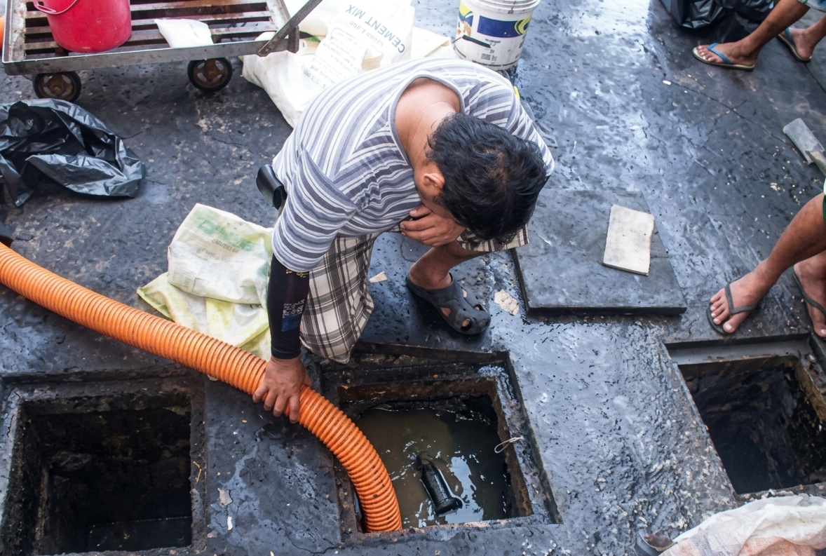 Crew working on septic tank siphoning with orange vacuum hose